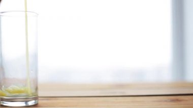 Portakal suyu ahşap masada cama dökülüyor.