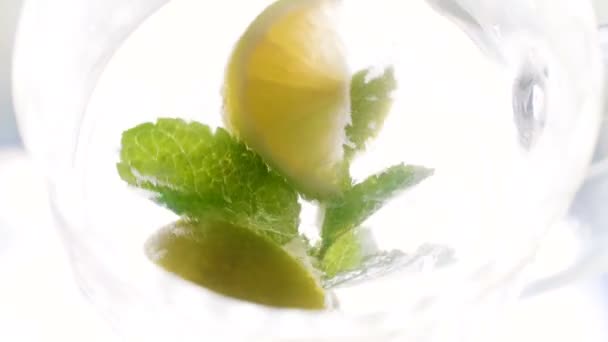 从顶部看柠檬片 冰块和薄荷叶在大玻璃杯中的旋转和漂浮 — 图库视频影像
