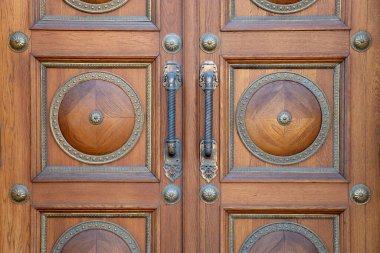 Güzel, eski, ahşap, kahverengi ön kapının bir kısmını altın sarısı kollarıyla kapat.