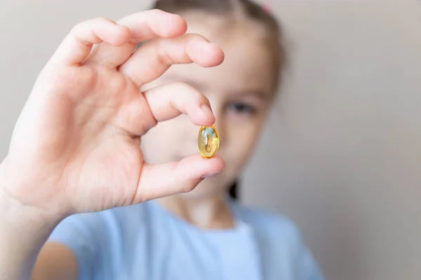 Omega-3 vitamini ve balık yağıyla elinde tutan çocuğu kapat.