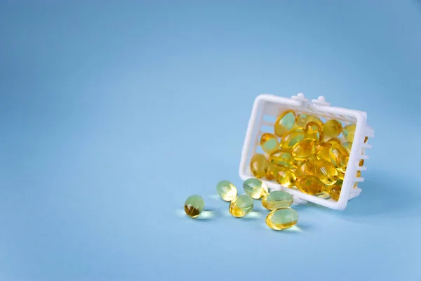Omega 3 vitamin takviyesi kapsülleri mavi arka planda izole edilmiş ve fotokopi alanı var. Balık yağı, D vitamini takviyeleri. Vitamin ve beslenme takviyeleri satın alma kavramı