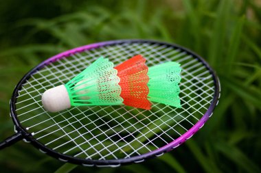 Badminton raketi ve yeşil çimen arka planında üç mekik horozu. Açık hava oyunları kavramı, doğada sağlıklı bir tatil.