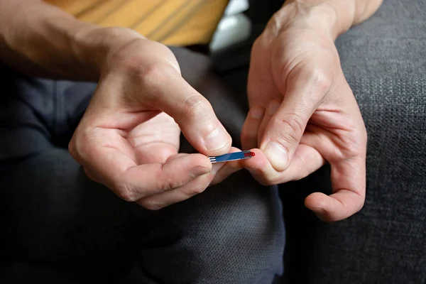 Adam şeker seviyesindeki kanı kontrol ediyor. Evde yapılan tıbbi testler. Kan şekeri testi kavramı. Test şeridi. Glisemi, diyabet. Adım adım talimat. Adım 3