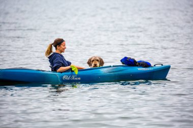 Pickeral, Wisconsin, ABD 12 Haziran 2018. Crane Gölü 'nde köpeğiyle eski bir kanoda oturmuş gülümseyen bir kız..