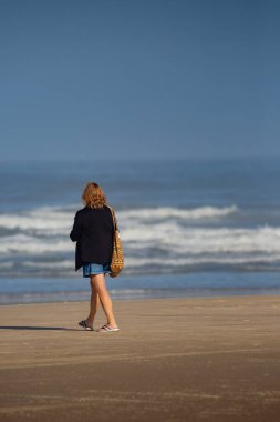 Oregon 'da okyanusun kıyısında yürüyen kadın, dikey.