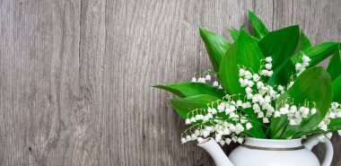 Vadinin zambakları beyaz bir çaydanlıkta duruyor. Ahşap bir arka planda. Ön manzara, pankart, kopyalama alanı.