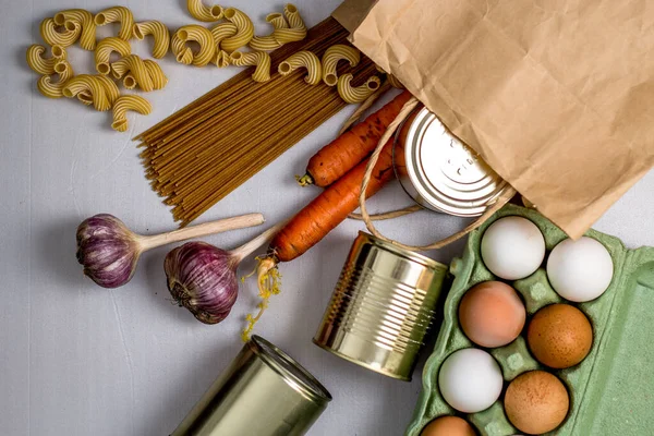 eggs in a box, canned food, pasta, spaghetti on a gray background form a grocery basket, essential food, products