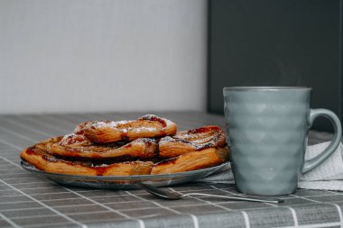 Elmalı puf böreği, tarçın ve pudra şekeri, masanın üstünde kareli masa örtüsü, turkuaz bardakta kırmızı çay, bir kaşık