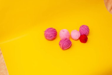 Sarı arka planda eflatun ve pembe renkli yün iplikler var.
