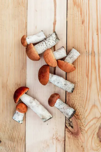 Birçok farklı yenilebilir mantar, tahtadan bir tahta üzerinde kahverengi renkli, toplanmış mantarlar üzerinde yatar. Yukarıdan görünüm