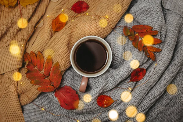 Otoño, hojas rojas secas del otoño mienten en suéteres que se apilan alrededor de una taza caliente del espresso, alrededor miente una guirnalda llevada, Flatley — Foto de Stock