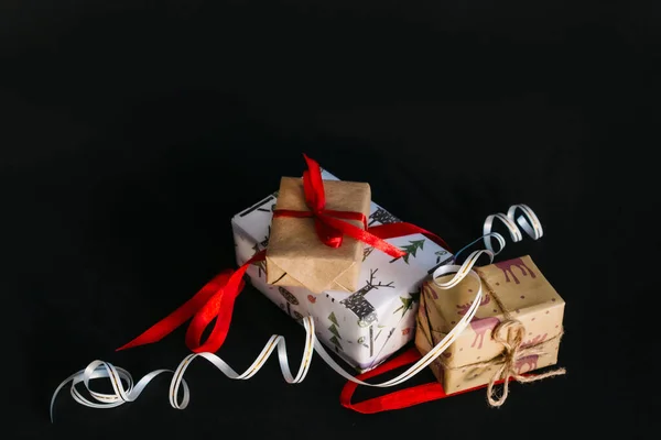 Auf Schwarzem Hintergrund Sind Weihnachtsgeschenke Geschenkpapier Eingewickelt Und Mit Bändern — Stockfoto