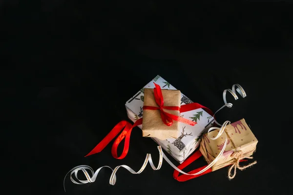Auf Schwarzem Hintergrund Sind Weihnachtsgeschenke Geschenkpapier Eingewickelt Und Mit Bändern — Stockfoto