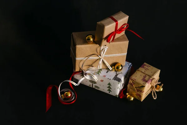 gift boxes Packed in wrapping paper and tied with ribbons for the New year or Christmas are on a black background, next to them are Golden Christmas balls. preparing for the holiday.