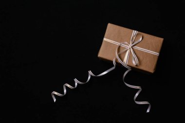 Noel için hediyeler, ambalaj kağıdına sarılı ve siyah bir arka planda kurdeleyle bağlanmış. Yukarıdan manzara. Düz.