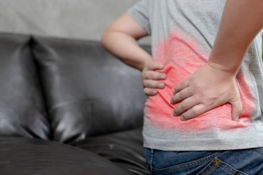 Sıkı çalışma nedeniyle bel ağrısı çeken genç bir adam, insan vücudu, ofis sendromu, kemik ve eklem hastalıkları, sağlık ve tıbbi bakım kavramları,.