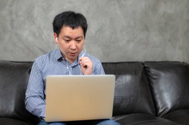 Taylandlı genç adam yüz maskesi takıyor. Bilgisayardan bilgisayar konuşması yapıyor. İnternet sohbetinde iş öğreniyor..