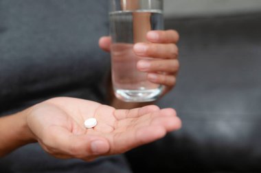 Kadın haplarını yakına alıyor. Hapları şişeden boşaltıyor. Ağrı, sağlık ve ilaç konseptini azaltmak için ağrı kesici alıyor..