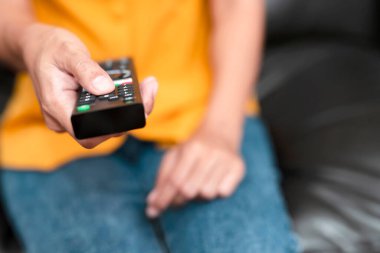 El, kanalı seçmek için uzaktan kumandaya basıyor. Boş zamanlarınızı evde film izleyerek geçirin..