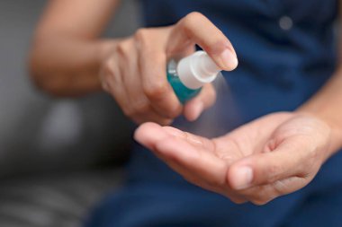 Bir kadının eli, Corona COVID-19 ve SARS Cov 2 enfeksiyonunu önlemek için antiseptik spay ile ellerini temizliyor. Evden çalışmak.