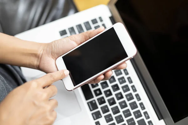 Çalışan kadın akıllı bir telefon ve bilgisayarla çalışıyor. Kadınların teknolojiyle çalışması kavramı.