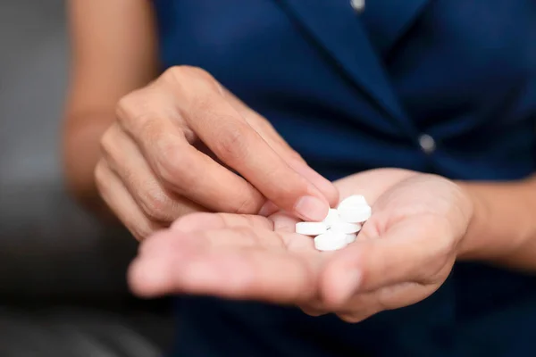 Close up of working woman taking in pill she is pours the pills out of the bottle,taking painkiller to reduce sharp ache concept,health care and medicine concept.