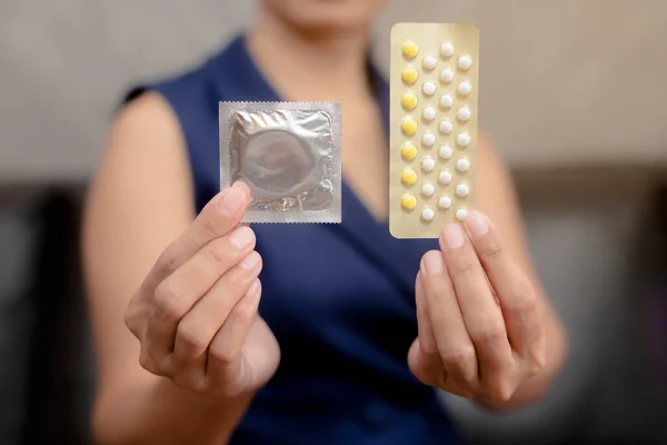 Doğum kontrol hapları ve prezervatif taşıyan kadın koltuk arkasında oturuyor, koruma, güvenli seks, doğum kontrol araçları....