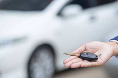Satıcının yeni sahibine anahtar verip otomobil fuarında el sıkışması. Araba satışı, anlaşma, konsept.
