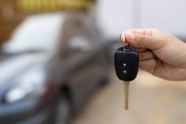 Satıcının yeni sahibine anahtar verip otomobil fuarında el sıkışması. Araba satışı, anlaşma, konsept.