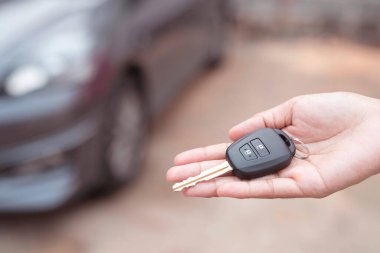 Satıcının yeni sahibine anahtar verip otomobil fuarında el sıkışması. Araba satışı, anlaşma, konsept.