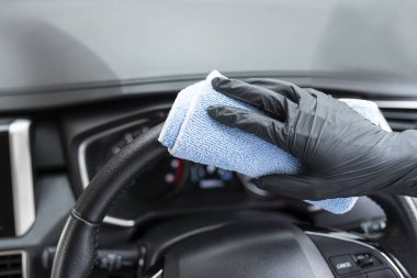Bu resim, arabayı eldiven takan mavi bir mikrofiber bezle silerken çekilmiş..