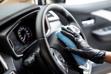 Bu resim, arabayı eldiven takan mavi bir mikrofiber bezle silerken çekilmiş..