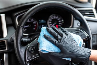Bu resim, arabayı eldiven takan mavi bir mikrofiber bezle silerken çekilmiş..