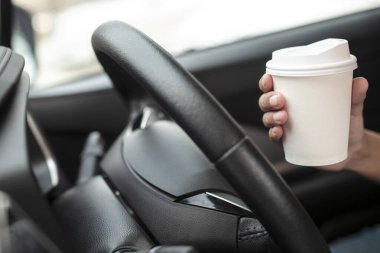 Kadın, sabahın köründe araba sürmeden önce elinde sıcak kağıt bardak kahve ile arabada oturuyordu. ulaşım ve araç kavramı.