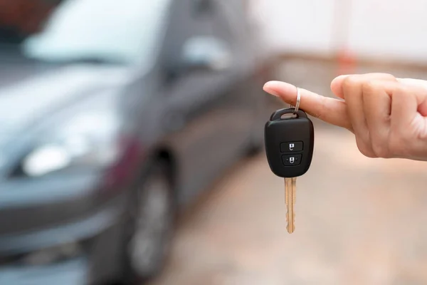 Close up of dealer giving key to new owner and shaking hands in auto show.auto business, car sale, deal,concept