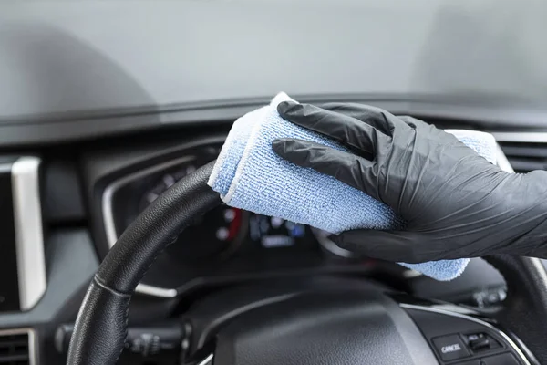 Bu resim, arabayı eldiven takan mavi bir mikrofiber bezle silerken çekilmiş..