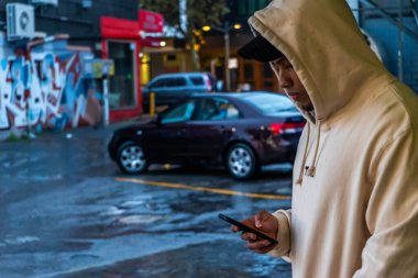 Telefonundaki kapüşonlu model Perth, Batı Avustralya 'da park halindeki arabalarla dolu binaya yerleştirilmiş.