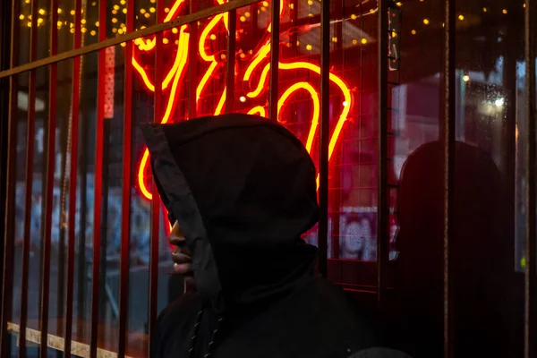 Neon tabelanın yanında poz veren adam ağzından çıkan alevler gibi görünüyor.