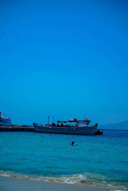 Tahta bir masası ve kumlu sahilde sandalyeleri olan Naxos plajı