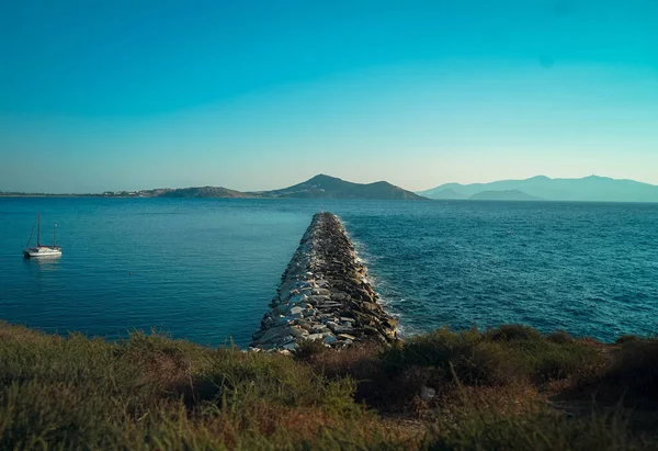 从海岸伸出来的一长串岩石在希腊岛上的海面上 — 图库照片
