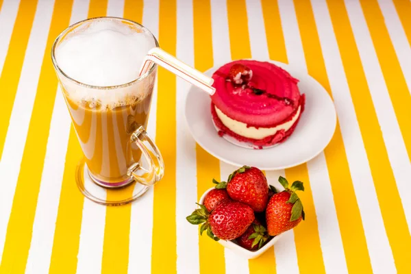 Uma chávena de café irlandesa, um bolo de framboesa, morangos doces frescos em um fundo branco e amarelo listrado . — Fotografia de Stock