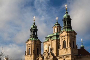Prague, Çek Cumhuriyeti için St. Nicolaus Kilisesi'nin kuleleri. Güneş ışığı tarafından golden, haçlar ve kulenin sonunda birlikte içine renkli cephe. Bulutlu gökyüzü.