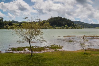 Göl Lagoa das Furnas Sao Miguel Island, Azor Adaları, Portekiz. Taze bitki örtüsü sahile astar. Mavi gökyüzü yoğun bulutlar ile.