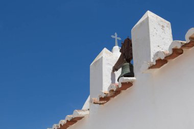 Bir beyaz kilise Nossa Senhora da Rocha Porches, Algarve, Portekiz bir detay diyagonal bileşimi. Bellfry, kenar bir çatı ve bir haç. Parlak mavi gökyüzü.