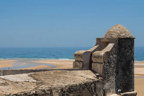 Taştan yapılmış eski kale kule. Su birikintileri ile kumlu bir plaj sonra yüksek gelgit görüntüleyin. Ufuk Atlantik Okyanusu'nun. Mavi gökyüzü. Cacela Velha, Algarve, Portekiz.