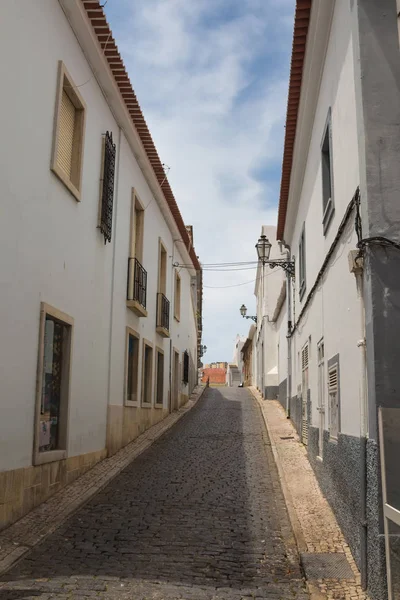 狭窄的街道上的小山两旁的白色房屋和鹅卵石铺平 传统灯笼 线的屋顶瓷砖 多云的天空 拉各斯 阿尔加维 葡萄牙 — 图库照片