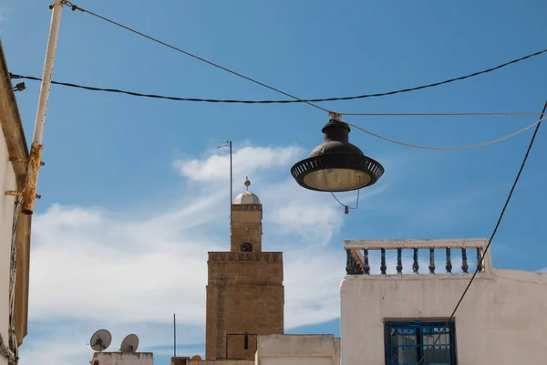 路灯挂在房子之间的电缆 传统建筑和清真寺的尖塔在背景 多云的天空 拉巴特 摩洛哥 — 图库照片