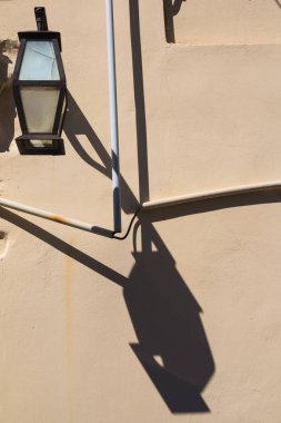 Eski bir fener ve onun gölge ışık turuncu duvar. Başka bir gölge bir kablo boru. Geleneksel köy Archanes, ada Crete, Yunanistan.