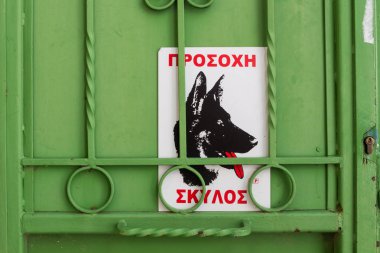 Yeşil kapı kilit ve bir uyarı Yunan alfabesinde bir köpek ile bir işareti. Yeşil Iron gate. Archanes, Crete, Yunanistan.