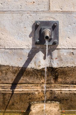 Duvar musluk suyu ve koşma su taşlarla yapılmış. Serinlemek için açık havada insanlar. Estoi, Portekiz.